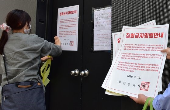 图为5月12日，韩国釜山镇区的公务员正在西面一带娱乐场所门口张贴禁止人员聚集的行政命令。宋奉根 记者