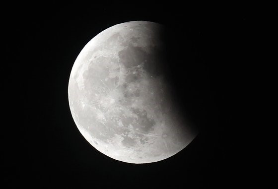 图为5月26日晚，从首尔松坡区观测到的月亮完全被地球阴影覆盖的月全食现象。【照片来源：韩联社】