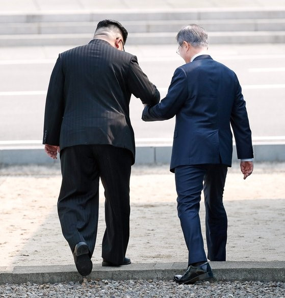 图为2018年4月27日，在韩朝举行首脑会谈的当日上午，文在寅总统和朝鲜国务委员长金正恩携手向北跨过军事分界线(MDL)。