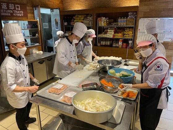 为韩国东京奥运会代表团提供餐饮保障的大韩体育会供餐支持中心的厨师们正在租赁的酒店厨房中做料理。【照片来源：韩联社】
