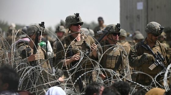 8月20日(当地时间)，塔利班控制阿富汗后，美军在喀布尔机场附近道路的铁丝网另一边看着想要逃离阿富汗的阿富汗人。【法新社=NEWS1】