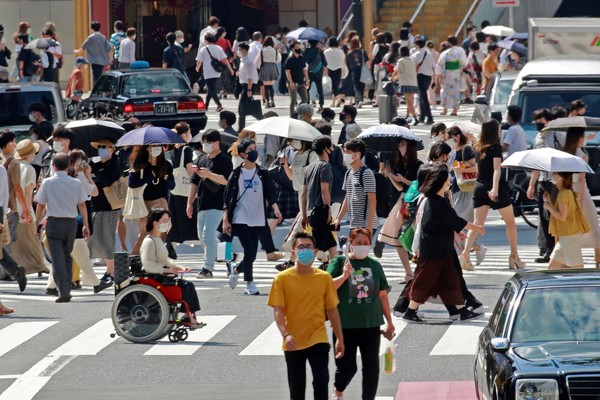 图为30日日本东京的情景。人们戴着口罩在大街上步行。【照片来源：美联社=韩联社】