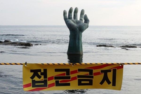 为防止新冠肺炎疫情进一步扩散，韩国政府决定将从31日起连续三天限制开放韩国境内山、海附近的国立公园。因此，新年来临之际，游客们将无法前往包括汉拿山、智异山等国立公园在内的韩国日出名胜观赏日出。普信阁敲钟活动也将改为线上举行，由地方政府主办的年末、年初活动也将陆续取消。图为29日，庆尚北道浦项市南区虎尾串面日出广场前的“相生之手”前挂上了“禁止游客出入”的告示。 【照片来源：NEWS1】