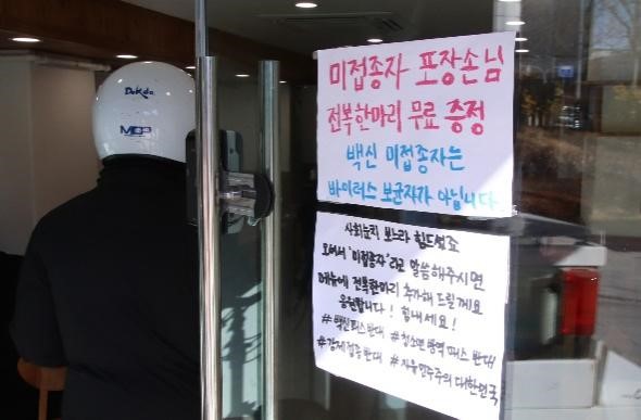 图为1月4日首尔江西区一家餐厅贴出了“打包的未接种疫苗顾客免费赠送鲍鱼一只”和“未接种疫苗者不是病毒携带者”的告示。  【照片来源：NEWSIS】