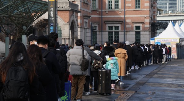 图为1月23日下午，在首尔站广场的新型冠状病毒筛查检测所，市民们正在排队等待检测。【照片来源：韩联社】