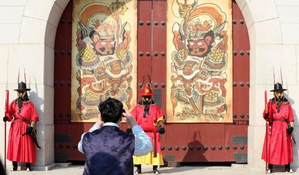 图为26日下午，相关人士正在首尔钟路区光化门前用手机拍摄当天公开的门神图。韩国有在正月初一在宫殿正门贴画以驱邪求福的风俗，此时贴的画被称为“门排图”。 【照片来源：NEWSIS】
