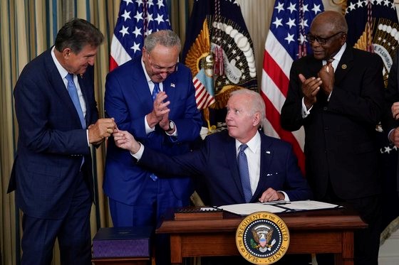 图为美国总统拜登当地时间16日在白宫签署《通胀削减法案》后将笔交给参议员曼钦。【照片来源：美联社=韩联社】