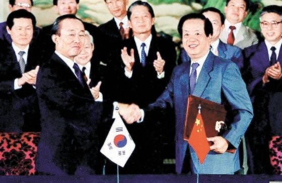 图为1992年8月，韩国时任外交部长李相玉和中国时任外长钱其琛签署并交换中韩建交文件后握手致意。【照片来源：中央图片库】