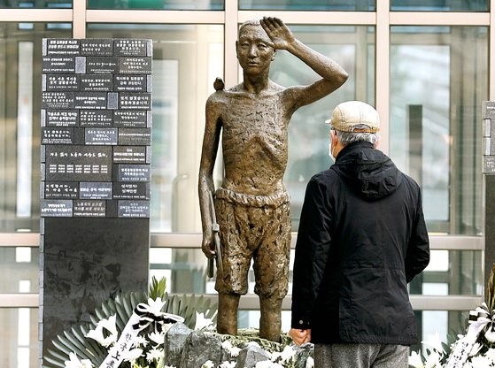 图为5日，一位市民在首尔龙山站广场观看强征劳工铜像。【照片来源：NEWS1】