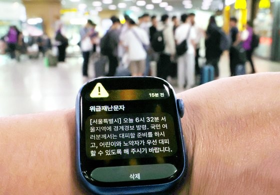 图为31日，在首尔站候车室，一位市民的智能手表上显示出危急灾难预警信息。【照片来源：韩联社】
