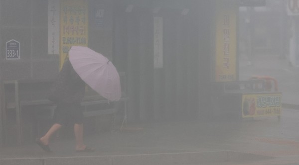 图为10日上午在庆南统营市江口内周边有市民正撑着雨伞艰难行走。统营地区被预报为第6号台风"卡努"的登陆路口。【照片来源：韩联社】