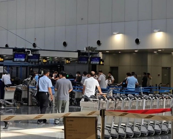 图为22日在北京首都机场第二航站楼的朝鲜高丽航空柜台上，朝鲜乘客正在托运行李。【照片来源：朴成训 记者】