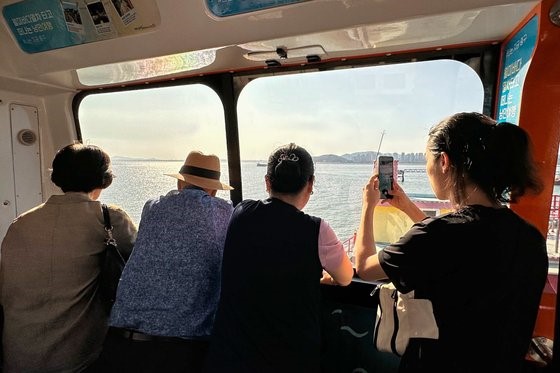 图为乘坐月尾海列车去月尾岛的人们，大家可以看到充满生机的港口风景和西海。