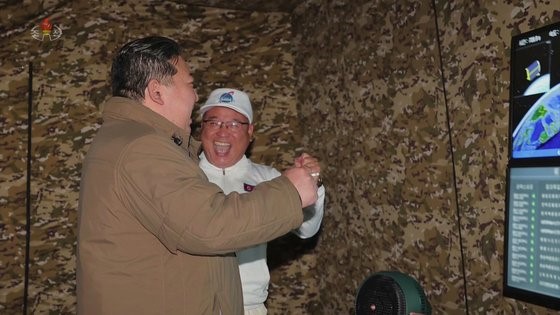 朝鲜委员长金正恩(左)和劳动党中央委员会副部长金正植(右)在成功发射勘测卫星“万里镜-1”后欢呼。【照片来源：朝鲜中央电视台=韩联社】