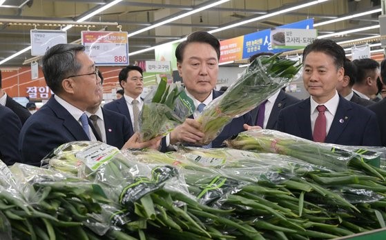 图为18日，韩国总统尹锡悦来到首尔瑞草区Hanaro超市良才店蔬菜柜台正拿起一把大葱查看。【照片来源：韩总统室摄影记者团】