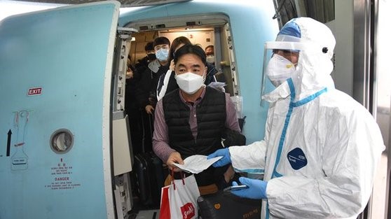 图为4月25日，抵达中国青岛的乘客正按照防疫人员的要求，测量体温。【中国新华网截图】