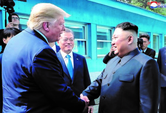 图为2019年6月30日下午，美国总统特朗普和朝鲜国务委员长金正恩在板门店握手。文在寅总统在一旁观看。【韩联社】
