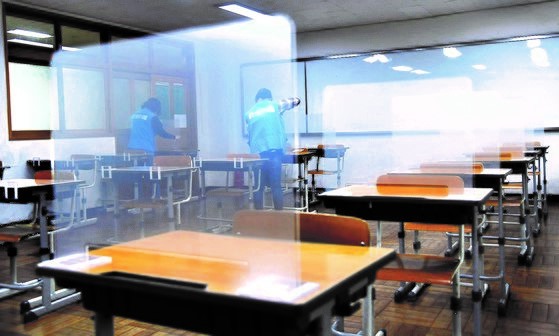 图为去年年底距离韩国高考仅剩一周的11月26日，在釜山南区盆浦高中教室中，相关工作人员正在学生课桌上安装半透明聚丙烯(PP)板。【照片来源：NEWSIS】