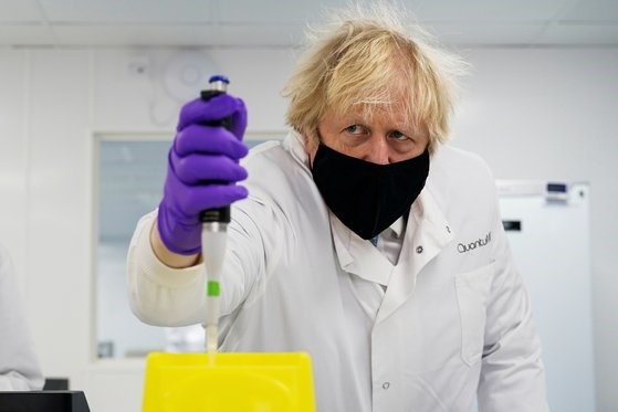 图为2月13日(当地时间)，英国首相鲍里斯戴着口罩参访位于英国纽卡斯尔的生命科兴仪器公司QuantuMDx观察该公司的实验设备。【路透社=韩联社】