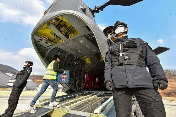 图为2月19日下午，在京畿道利川市特战司令部直升机场举行的“疫苗流通第二轮泛政府联合模拟演习”中，负责运输的人员正在往运输直升机(CH-47D)上搬运疫苗模型。【照片来源：共同摄影团】