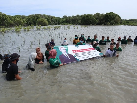 图为在防弹少年团成员朴智旻敏的生日之际，在印尼中部爪哇岛海岸种植红树林树苗的防弹少年团粉丝和志愿者。【照片来源：Lindungihutan】
