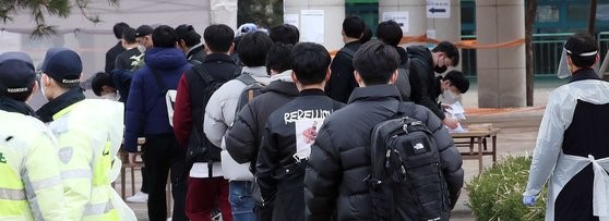 在持续的就业困局下，韩国举行了2021年第一次警察公务员招录笔试。图为3月6日上午，应试考生正在首尔中区城东工业高中的考场排队进场。警察厅的数据显示，本次考试共招录2907名警察公务员，报名人数达到4.6687万人，竞争率为16比1。【照片来源：NEWS1】