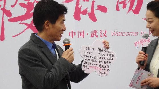 图为3月18日，在中国武汉东湖樱花公园举行的“2021年樱花节”现场，韩国驻武汉总领事姜承锡正在朗读韩国诗歌《樱花的一生》。【申庚振 记者】