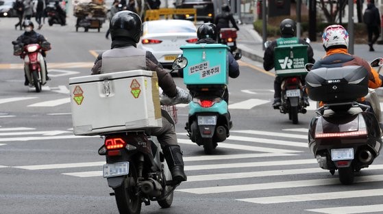 图为3月2日在首尔市区骑着摩托车送外卖的骑手们。【照片来源：韩联社】
