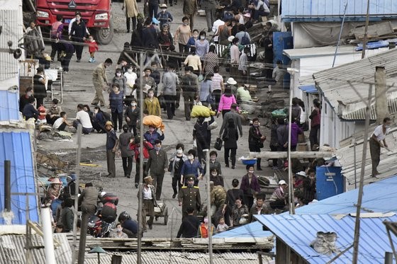 图为去年9月在朝鲜两江道惠山市的集市可以看到戴着口罩的人们往来走动。这是从中国吉林省长白朝鲜族自治县拍摄的照片。【照片来源：韩联社】