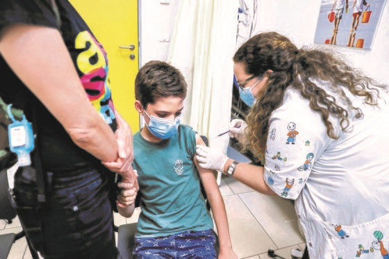6月21日，在以色列特拉维夫附近霍隆市某诊疗所，一名10多岁的儿童正在接种新冠肺炎疫苗。以色列政府部门强烈建议12-15岁的儿童和青少年一起接种疫苗。在德尔塔变异毒株重新扩散后，以色列从6月22日起建议民众重新在室内戴上口罩。【法新社=韩联社】