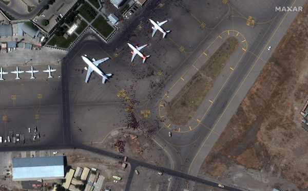 从MAXR和PlanetLab等公布的卫星照片来看，大量人群涌入喀布尔国际机场，导致现场极度混乱。人群涌入机场跑道，想要搭上离开阿富汗的飞机。MAXR在8月16日(当地时间)拍摄的阿富汗喀布尔国际机场飞机跑道上聚集的人群(黑点部分)。【欧新社=韩联社】