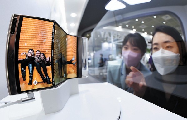 8月25日，韩国显示器产业展览会(IMID 2021)在首尔江南区COEX开幕。图为当日上午，在三星显示器公司展台，三星的相关人士正在观看可以双重折叠的S型产品(Flex In & Out折叠屏，上方照片)。LG显示器公司展出了可以安装在智能床上的OLED显示器。韩国显示器产业协会主办的这一展会将在8月27日闭幕。【照片来源：韩联社】
