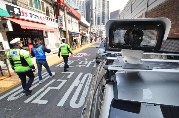 韩国从21日起开始全面实施禁止在儿童保护区内停车的《道路交通法修订案》。若驾驶员在管制时间(早8时至晚8时)有违章行为，将被处以12万韩元(以轿车为准)罚款，是普通道路的3倍；接送儿童上下学的车辆也需要在专用区域内停车。 图为当天在首尔一所小学附近，警察正在进行巡逻。 【照片来源：韩联社】