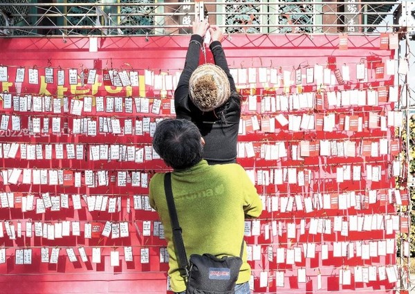 距离韩国2022学年高考(11月18日)还剩最后三天时间。图为11月14日在首尔曹溪寺拍摄到的为即将参加高考的子女加油祈福的家长正在往墙上贴心愿纸。【照片来源：NEWS1】