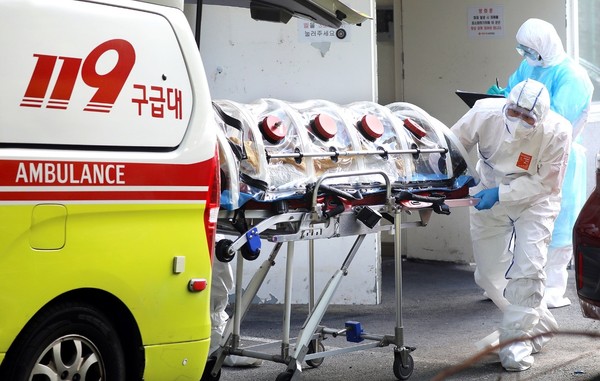 图为去年发生集体感染的釜山某疗养医院一名确诊患者正被推上119救护车转移到隔离医院。【中央照片库】