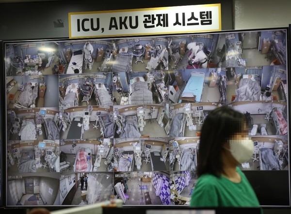图为11月24日，在韩国新型冠状病毒肺炎(COVID-19)定点收治医院平泽博爱医院的监控室，相关人员正从显示病房情况的病房管理系统显示屏前走过。【照片来源：韩联社】