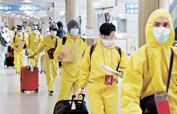 图为11月29日上午，仁川国际机场第1航站楼身穿防护服并头戴面罩的海外入境人员正在走过。【照片来源：NEWS1】