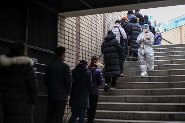 图为12月9日上午在首尔市松坡区松坡卫生所的新冠检测站点前排到地铁站口的市民们。【照片来源：韩联社】