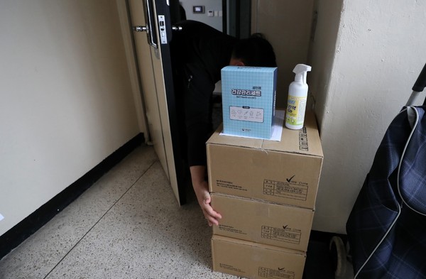 12月2日首尔某住宅楼感染新型冠状病毒肺炎(COVID-19)后开始“居家治疗”的市民收到卫生所送来的居家治疗专用健康管理配套物品。【照片来源：NEWSIS】