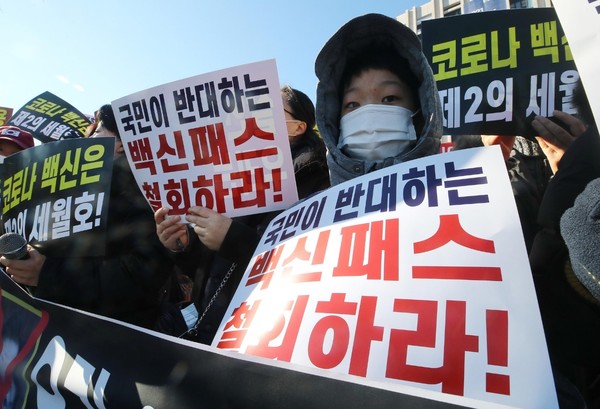 图为13日上午，在政府首尔大楼前举行的反对疫苗通行证及青少年疫苗接种记者会上，一名儿童也举起了标语。【照片来源：韩联社】