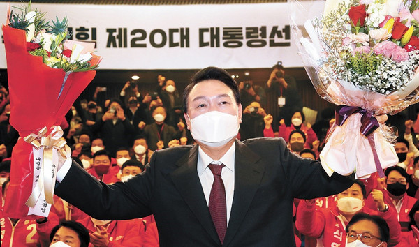 韩国候任总统尹锡悦3月10日清晨到首尔汝矣岛国会图书馆计票观察室，举起庆祝胜选的花束向人们致意。金京禄 记者