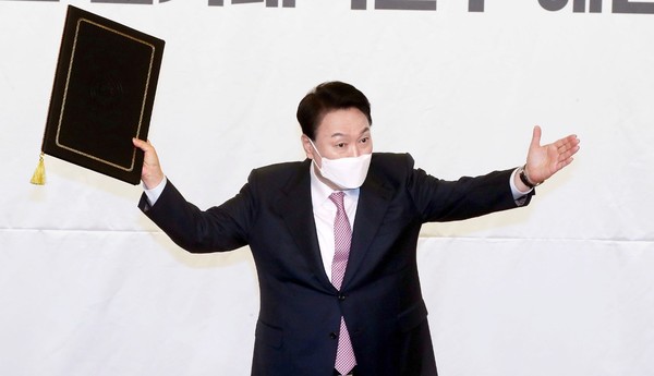 图为当选韩国第二十届总统的候任总统尹锡悦3月10日国民之力党选举对策委员会解散仪式上高举当选证书。国会摄影记者团