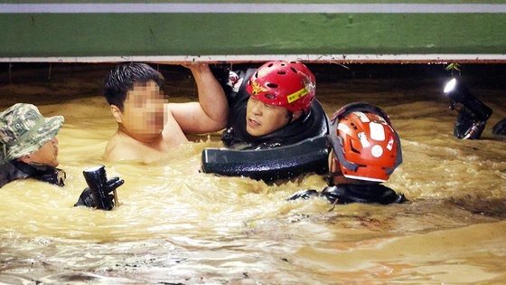 6日，第11号台风“轩岚诺”登陆，庆尚北道浦项和庆州因暴雨接连出现人员伤亡。据韩国消防当局报告，在浦项市南区仁德洞某公寓内，7名公寓居民为取车而进入被水淹没的地下停车场后失踪。韩消防当局展开搜救，截至当晚11时40分，共救出2名男性和3名女性，其中3人昏迷不醒。图为当天获救的一名30多岁男子正游出停车场。【照片来源：每日新闻】