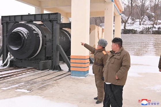 朝鲜国务委员长金正恩(右)12月15日在平安北道东仓西海卫星发射场基地参观“大功率固体燃料启动器”(火箭发动机)的地面点火试验。【照片来源：韩联社】