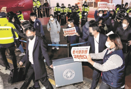 图为18日下午，韩国国家情报院和警方在对首尔中区民主劳总首尔办公室进行扣押搜查后，正拿着装有扣押物品的箱子离开。【照片来源：韩联社】