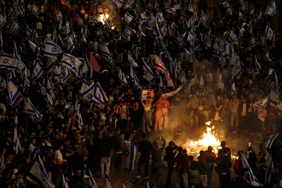 图为当地时间26日，反对以色列总理本雅明·内塔尼亚胡“司法改革案”的市民在以色列首都特拉维夫进行示威。当天，以色列最多有20万人参与了示威活动。以色列总理内塔尼亚胡解除了批评该法案的国防部长职务之后，示威活动随之逐渐扩散。因涉嫌腐败而在接受审判的内塔尼亚胡正在推进削弱司法部权力的立法。【照片来源：路透社=韩联社】