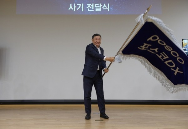 图为POSCO DX社长郑德均在30日举行的公司愿景宣布仪式上挥动员工代表递上来的公司旗帜。【照片来源：POSCO DX】