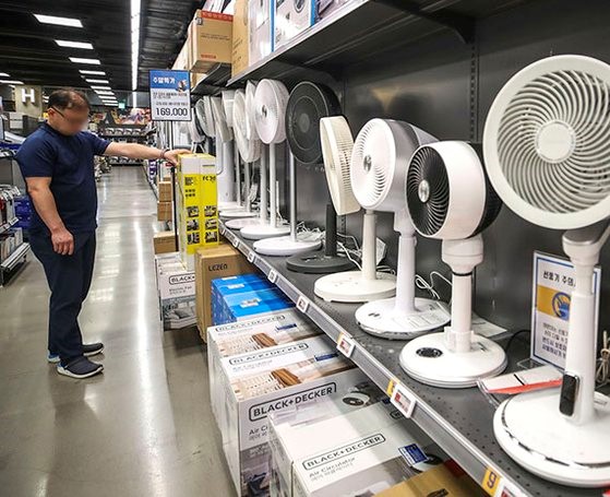 由于炎热天气提前到来、电费上涨等原因，电风扇大受欢迎。易买得表示，从4月开始到本月17日，电风扇的销售额比去年同期增加了34.3%。图为 21日来到首尔市内某大型超市家电卖场的市民正在看电风扇。【照片来源：NEWSIS】