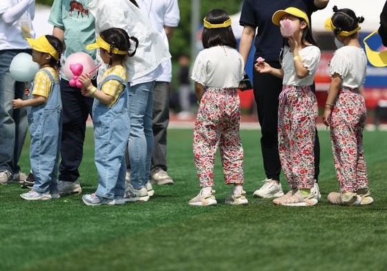 上月13日在首尔大学运动场举行的“Twins Plus Homecoming Day”活动上，小朋友们和父母一起排队等待收到气球礼物。【照片来源：韩联社】