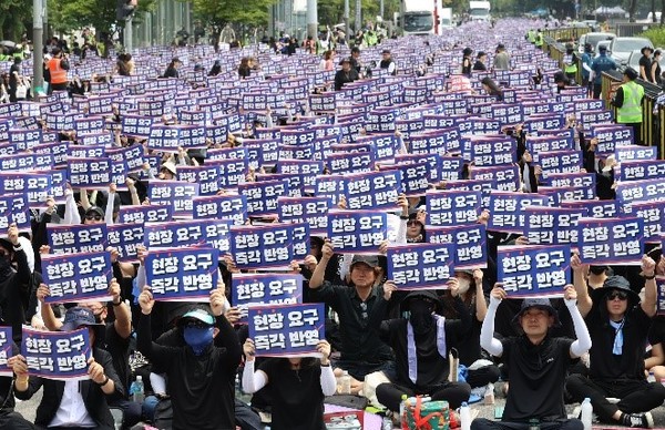 图为26日下午，在首尔永登浦区国会大厦前举行的全国教师“敦促国会立法追悼集会”上，参加者举着手牌子。【照片来源：韩联社】